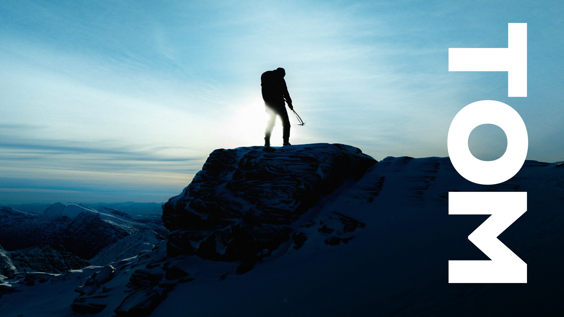 TOM — climber on mountain peak at dusk